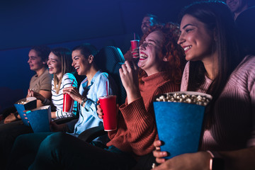 Group of cheerful people laughing while watching movie in cinema.