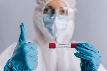 Coronavirus testing. The doctor holds in her hand a test tube with a blood sample with a negative result. Close-up. Selective focus.