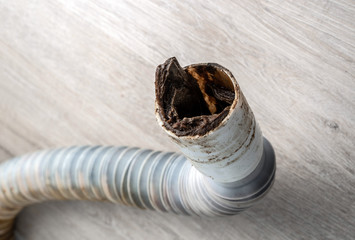 Clogged plastic corrugated drain pipe lies on the floor. Selective focus.