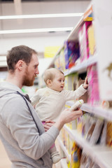 Obraz premium young father with small baby shopping at supermarket.