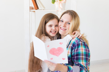 Mother's Day and family holidays - Mother reading greeting card from her daughter.