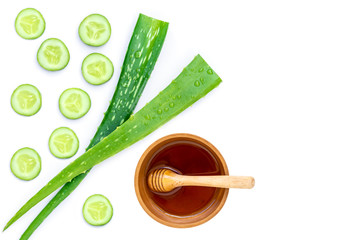 Green fresh aloe vera leaf with water drops and cucumber with honey in wooden bowl isolated on white background. Natural medicine plant,beauty and spa concept. Copy space for text and content.Top view