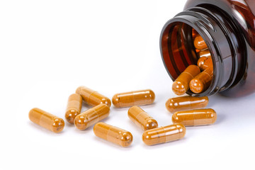 Closeup herbal turmeric capsules in brown plastic bottle isolated on white background.