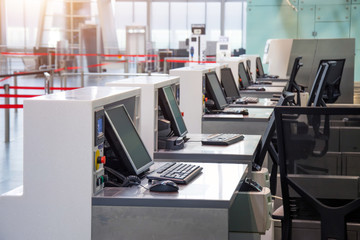 Row of empty check-in desks with computer monitors at the airport.