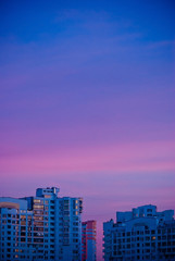 Fototapeta na wymiar Buildings in city at sunset. City illuminated by the last rays of the setting sun. Magical purple sunset. Minimalism. Place for your text