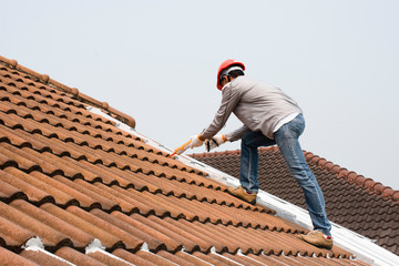 Technician man hand using glue gun with silicone adhesive or manual caulking gun with polyurethane to seal the leakage on the roof. Installing and building construction concept.