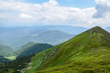 Fototapeta na wymiar Beautiful green mountain valley. Scenic grassy mountains. Summer day in mountains. Green hills and clouds on blue sky. Place for active recreation and hiking Marmarosy ridge. Ukraine