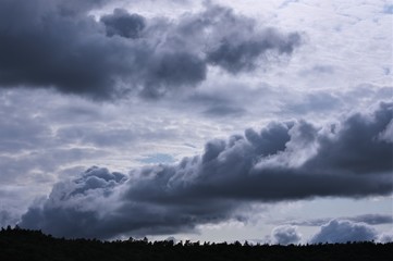 Obraz na płótnie Canvas Große, gewaltige, dunkle Gewitter- und Regenwolken über Wald am Horizont