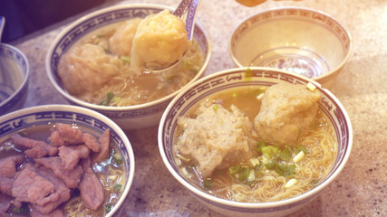 Eating Hong Kong Cantonese wonton beef and meat ball soup noodle
