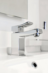 The new faucet in the bathroom is made of stainless steel with a modern design. Closeup, selective focus.