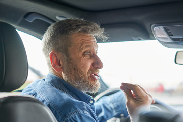 Portrait of a driver talking  in a very angry aggressive way and emphasizing his emotions with his...