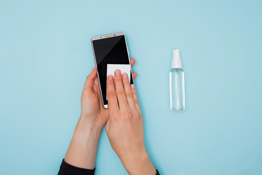 Woman Cleaning And Disinfecting Mobile Phone For Covid-19 Coronavirus Disease Prevention.