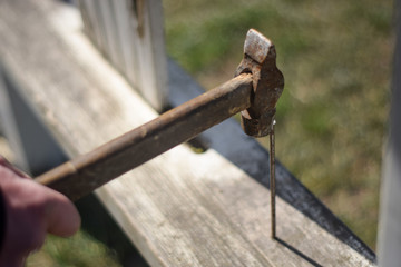 Worker hammer a nail into a wooden board. Old hammer in hand close up. Hammer in hand of engineer or handyman. Hand tool close up