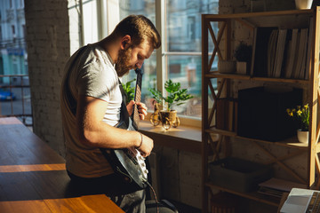 Caucasian musician playing guitar during online concert at home isolated and quarantined. Using camera, laptop, streaming, recording courses. Concept of art, support, music, hobby, education.