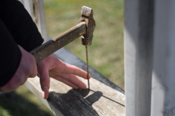 Worker hammer a nail into a wooden board. Old hammer in hand close up. Hammer in hand of engineer or handyman. Hand tool close up
