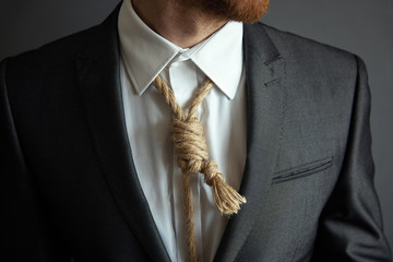Concept image of business in trouble. Man in suit with Lynch loop instead of tie over neck.
