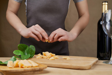 Cooking, food and home concept. Female Hands with knife, wine and cheese