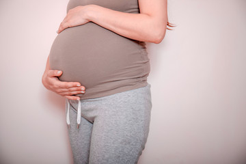 Pregnancy And Backache. Unrecognizable Pregnant Lady Touching Red Pain Zone On Back Sitting On Bed At Home. Cropped