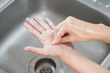 Fototapeta premium Close up woman hand washing under running water in the kitchen.Hygiene and cleaning Hands.Image hand washing step concept.