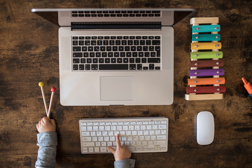 A child's hand playing on his father's laptop computer. Working from home. Coronavirus. Covid 19. Kids toys