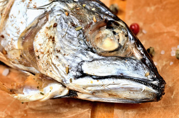 Close-up of smoked mackerel with garlic, pepper and coarse salt on baking paper.