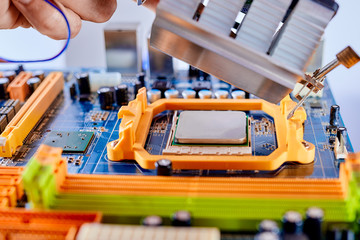 The technician is putting the CPU on the socket of the computer motherboard. Close up
