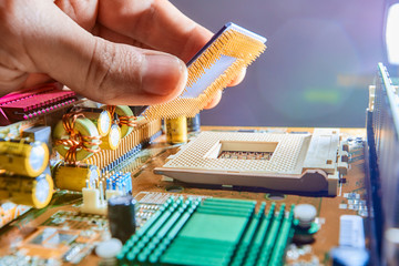 The technician is putting the CPU on the socket of the computer motherboard. Close up