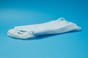 Stack of medical masks on a blue background.  Selective focus