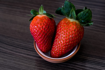 zwei rote süße Erdbeeren in einem weißen Schälchen