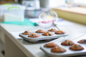Confectioner took out freshly baked muffins in a baking dish on the table from the oven
