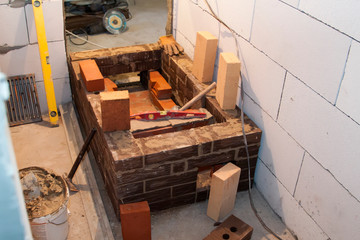 Sauna stove that is being built from fire resistant material in undeveloped interior laid out of foam blocks in country house under construction