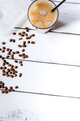 coffee break with cold iced latte and beans on white table background top view