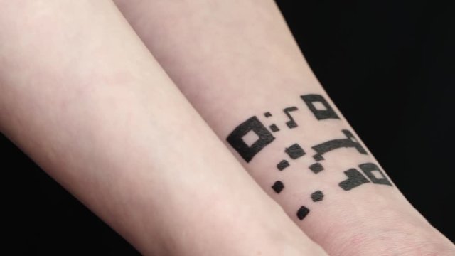 An unknown person shows parts of their hands with the image of a fictional QR code on their skin. The concept of using, quick access to personal data, chipping. Quarantine and tracking.