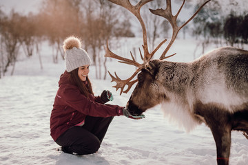 Chica con reno en la nieve. Invierno en Noruega