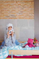 Portrait of a little girl wearing an astronaut helmet sit on the bed. Stay home concept during pandemic disease coronavirus covid 19. Feminism and equality of gender in toys for children.