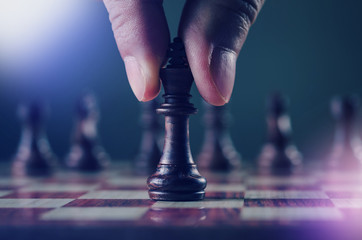 strategy and planning concept, close up human hand while holding or moving king chess piece in cool...