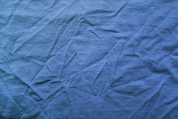 Wrinkled blue fabric texture, crumpled cloth background. Soft pale blue creasy clothing pattern, cotton material t-shirt or jacket, flat lay close up top view from above