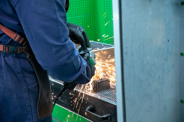 industrial worker cutting, grinding and polishing metal surface, aluminium case, producing sparks