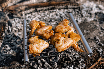 Lightweight, folding, portable grill for tourism, hiking, takes up little space, durable aluminum and steel. Cooking on a camping trip. Coal and smoke. BBQ Chicken Wings. Selective focus