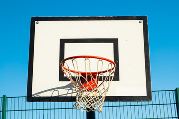 Basketball basket on the street against the blue sky