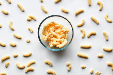 Sweet corn sticks in a glass bowl standing on white surface among other scattered around. Organization, collection concept.