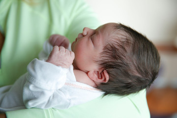 A newborn infant is held by her mother in the hospital
