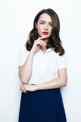 Young brunette woman with red lips and healthy clean skin, happy face with a smile. Beautiful woman in a white shirt and blue skirt posing in studio. 