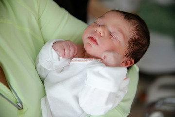 A newborn infant is held by her mother in the hospital