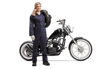 Fototapeta na wymiar Female motorcycle mechanic with a custom motorbike holding a tire