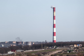 Fototapeta na wymiar Energy heat power station pipe with red white stripes. Europe, Ukraine industrial clear sky landscape with air pollution smoke tower