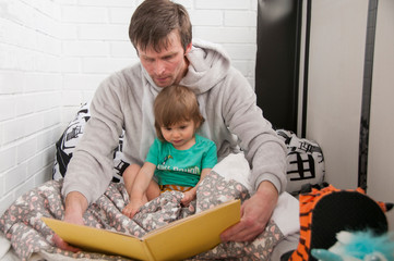 Young father reading book with his little daughter. Family at home.