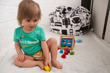 Baby girl playing with wooden educational game. Colourful toy. Playtime.