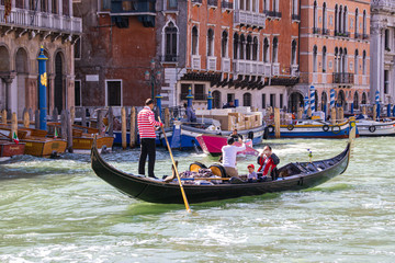 Fototapeta na wymiar Water channels of Venice city. Gondolier rolls tourists on the gondola on Grand Canal in Venice, Italy.