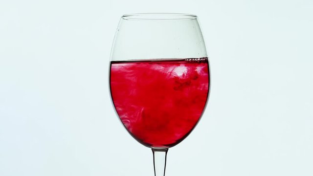 Wine glass filled and spreading red ink. Red wine fill the bowl. 